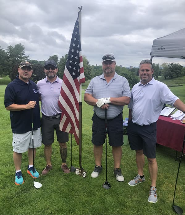 Four male golfers posting for picture with golf clubs.