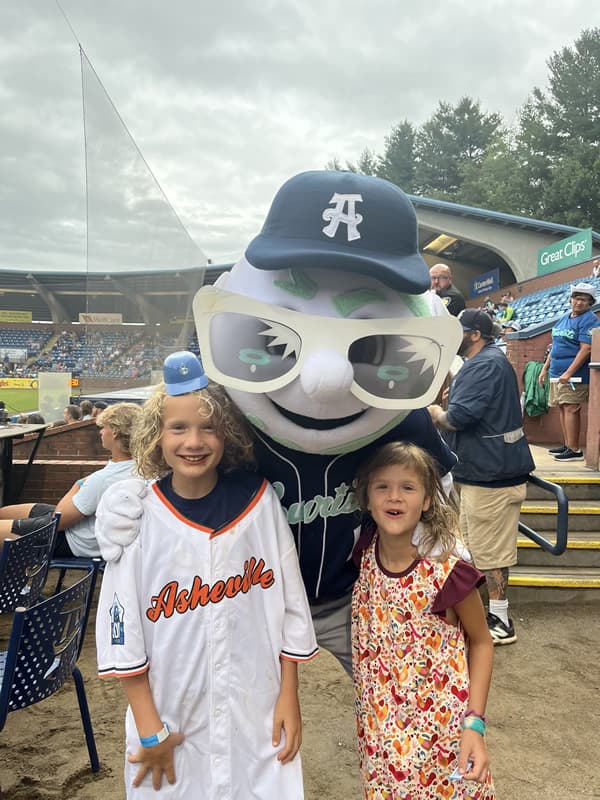 Tourist mascot with arm around two young girls.