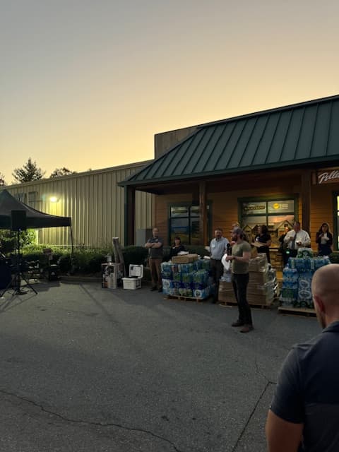Person talking in front of supplies and building.