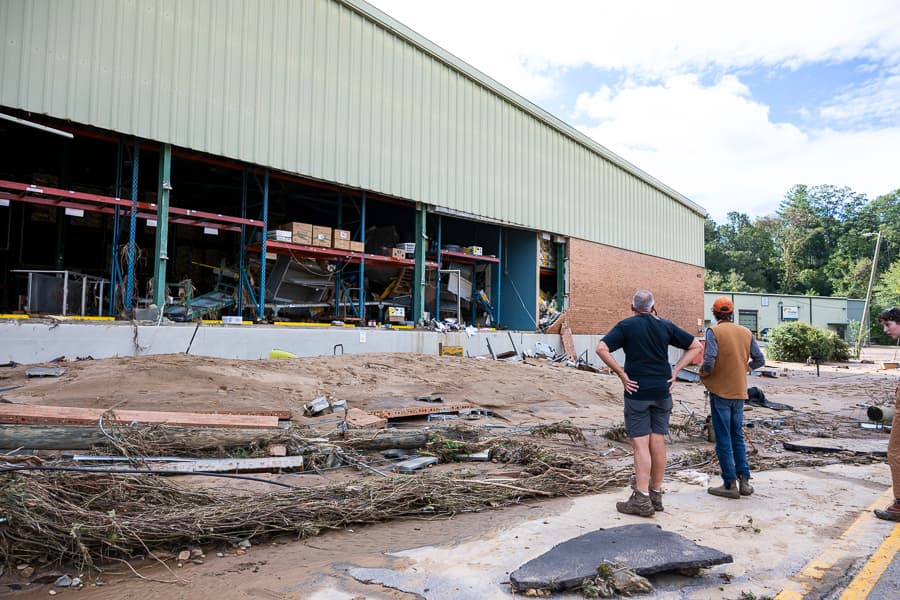 Two men assessing damage to building after Hurricane Helene.