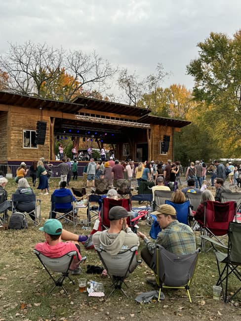 Audience sitting on lawn watching musicians.