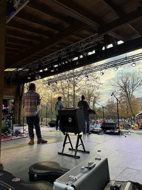 Shot of the back of musicians on stage playing for outdoor audience.