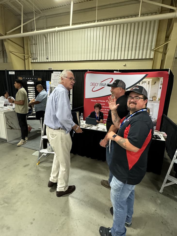 People at an event with booths, one waving.