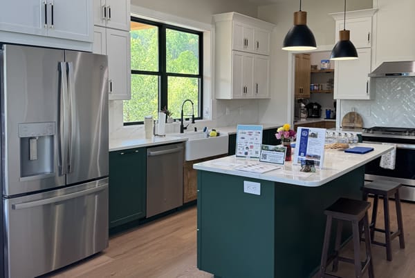 Display during Parade of Homes in a modern kitchen with white cabinets and a teal island.